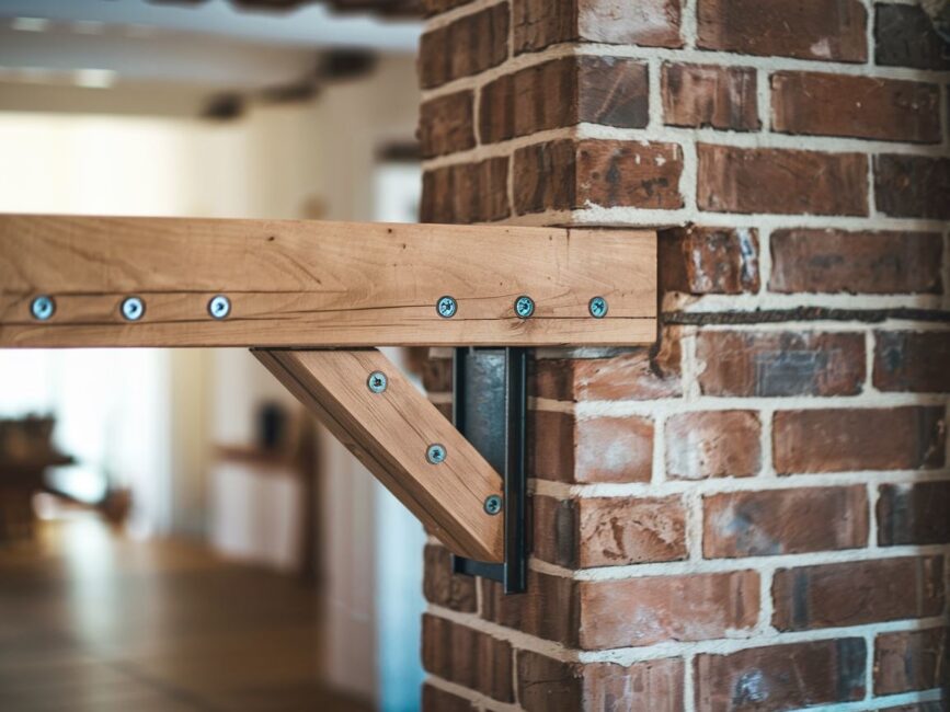 Konstrukcja z belką drewnianą na tle ceglanej ściany